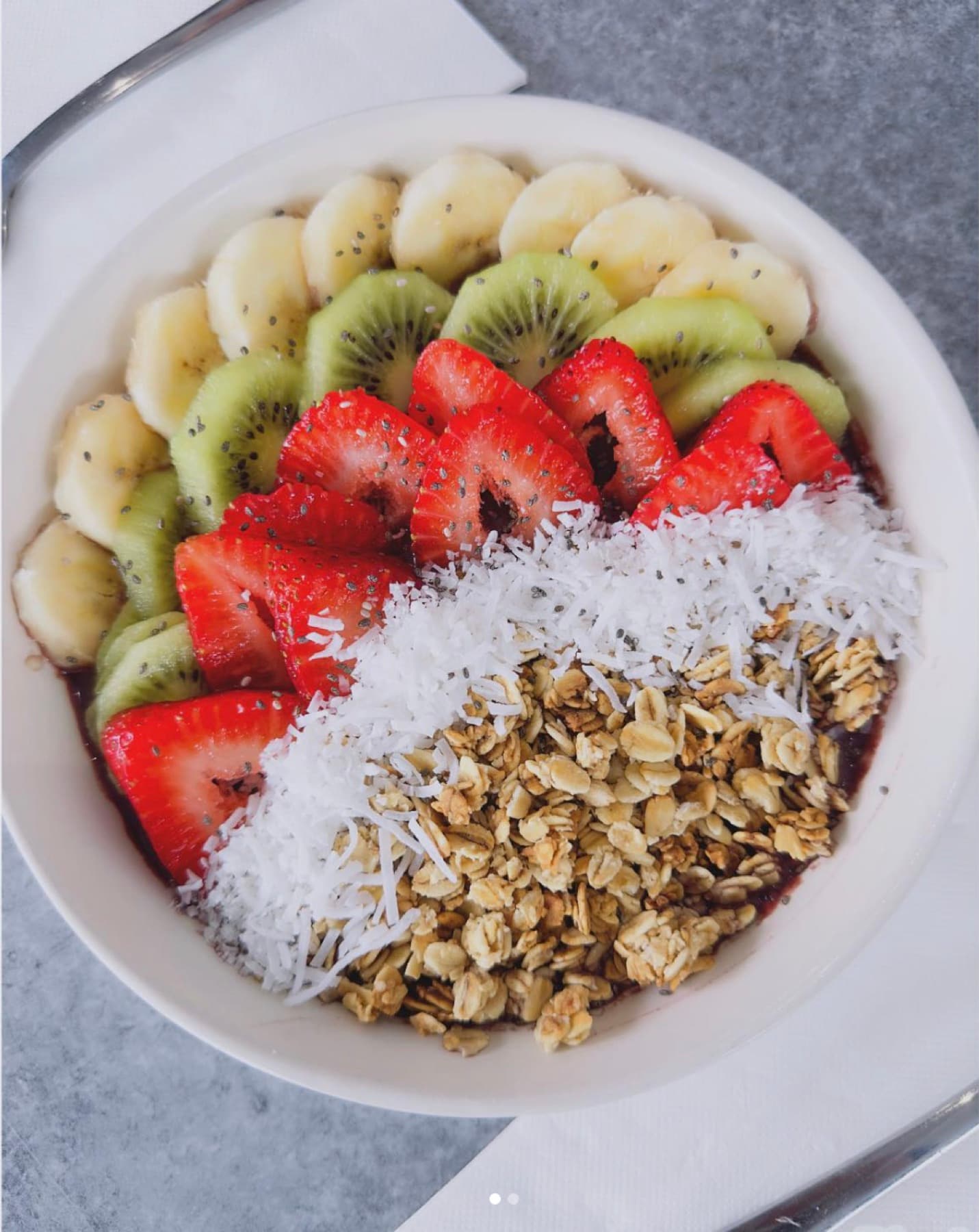 Açaí bowl topped with banana, kiwi, strawberry, coconut and granola