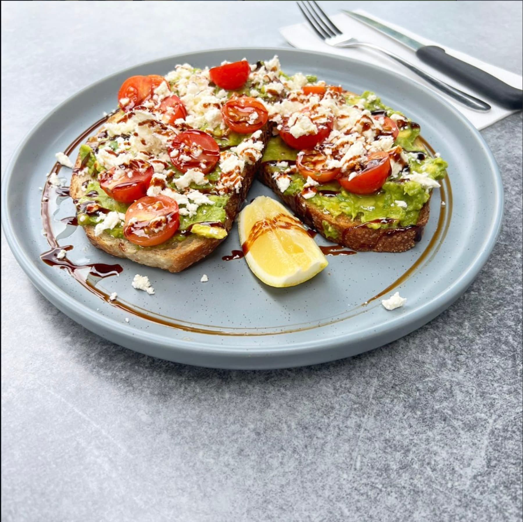 Smashed avocado on sourdough with feta, cherry tomatoes and balsamic glaze