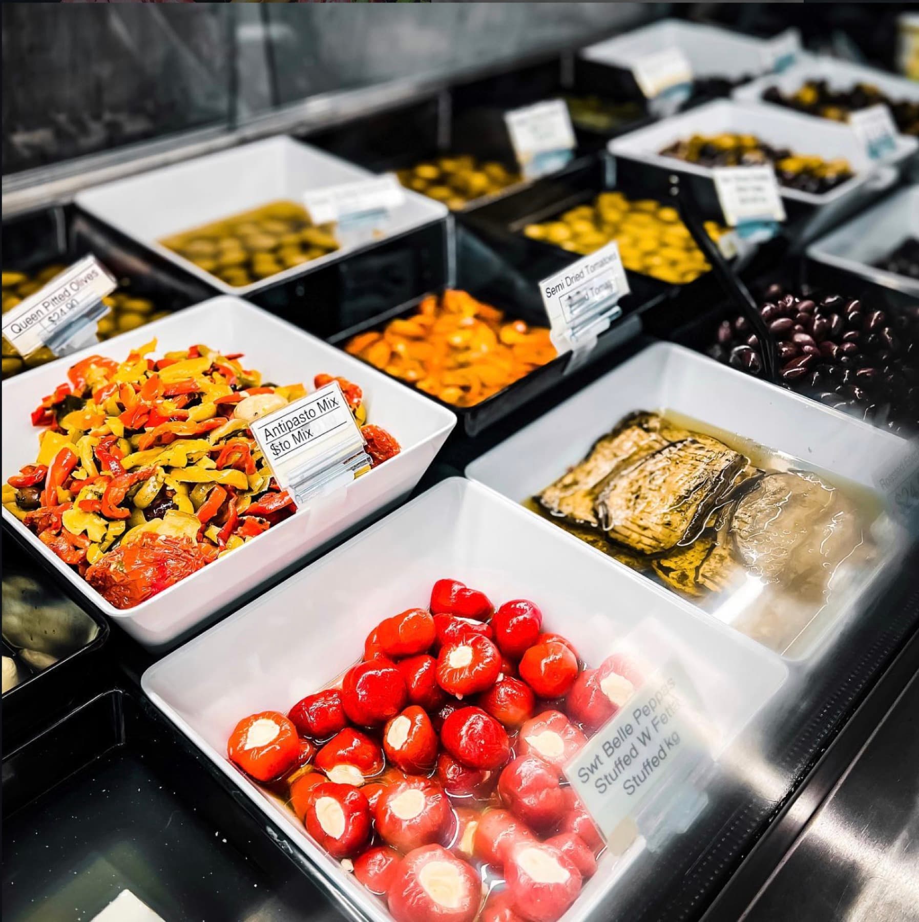 Deli case with marinated peppers, semi-dried tomatoes, olives, artichokes and stuffed peppers
