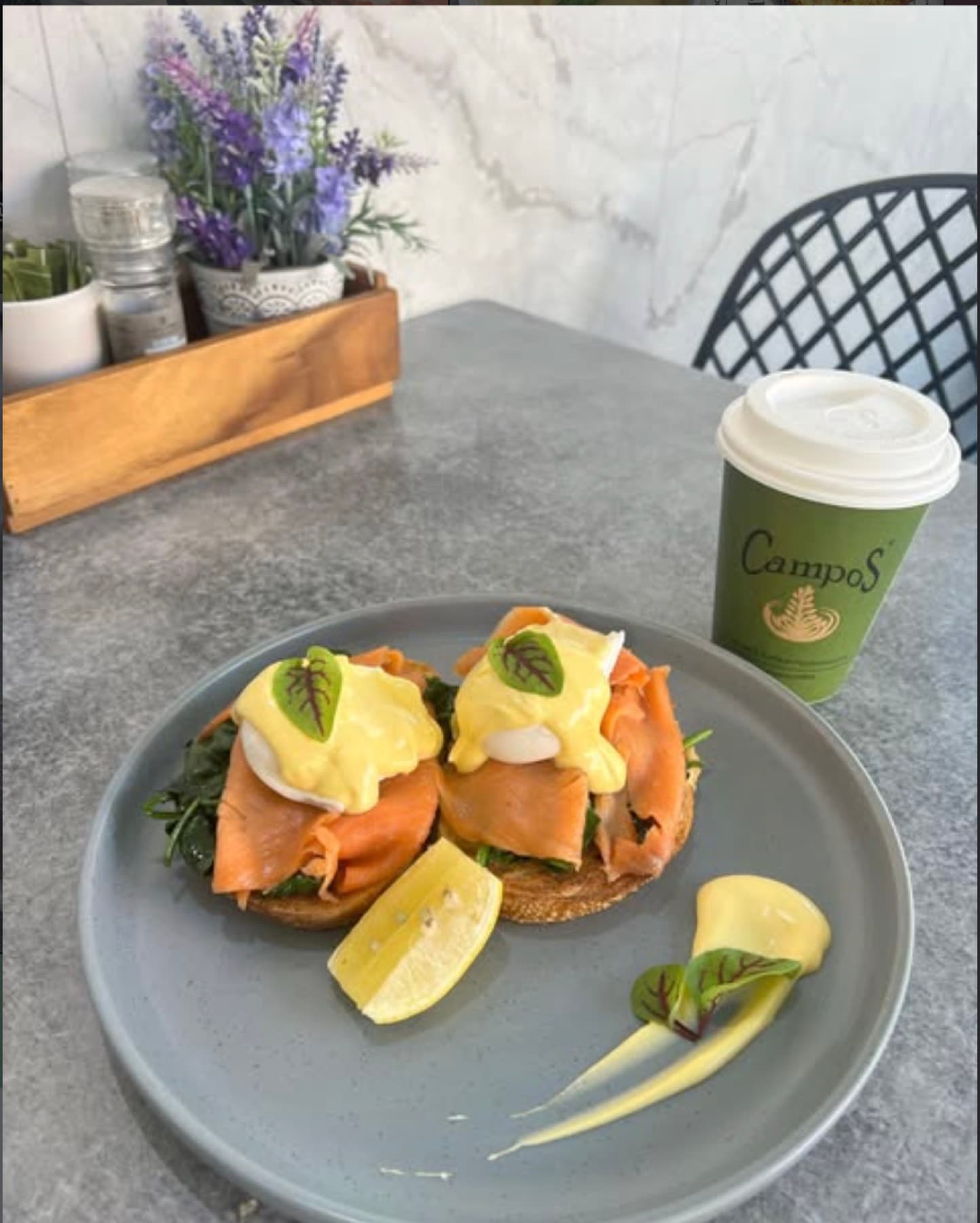 Eggs benedict with smoked salmon and hollandaise, beside a takeaway coffee