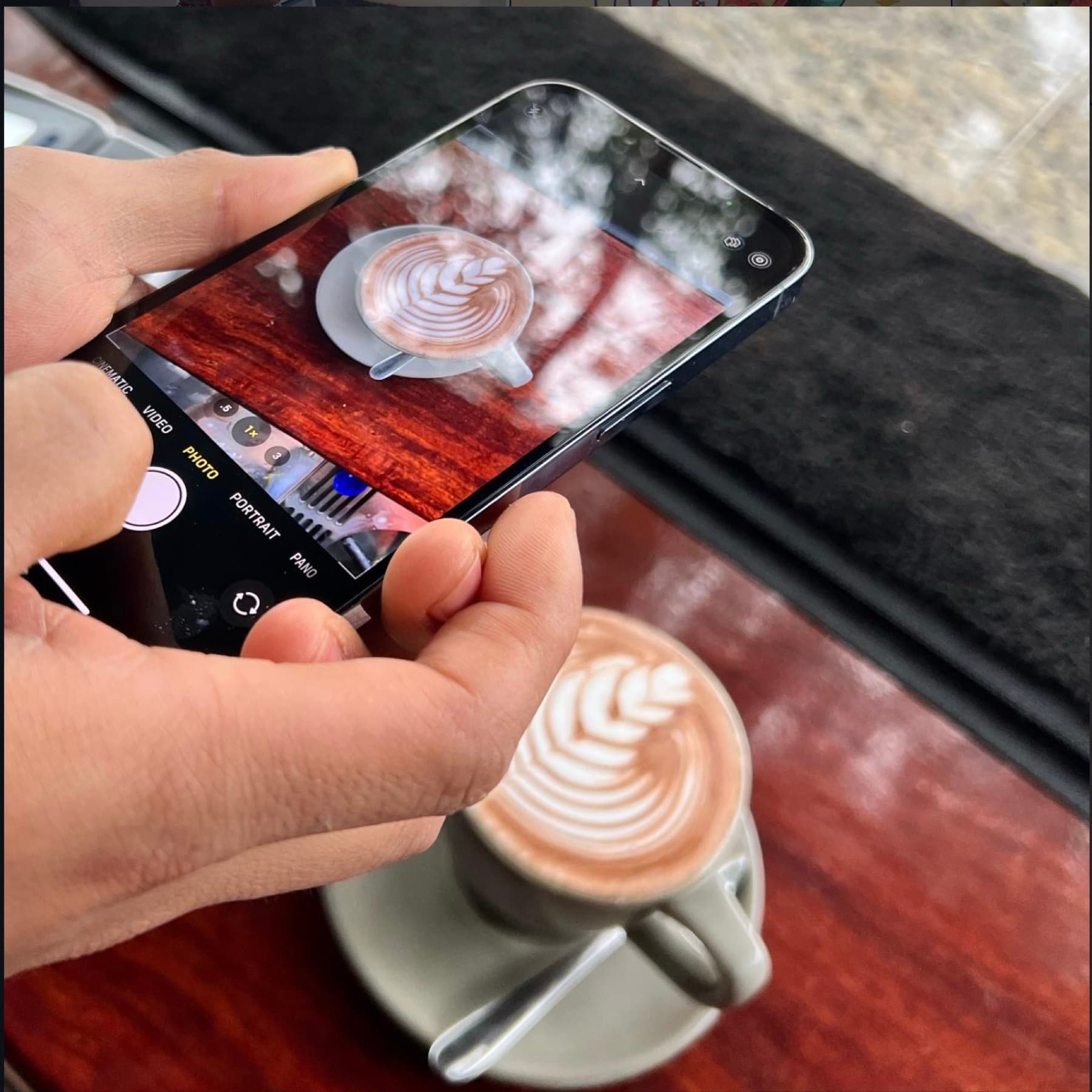 Someone photographing a cappuccino on a phone at the timber bar