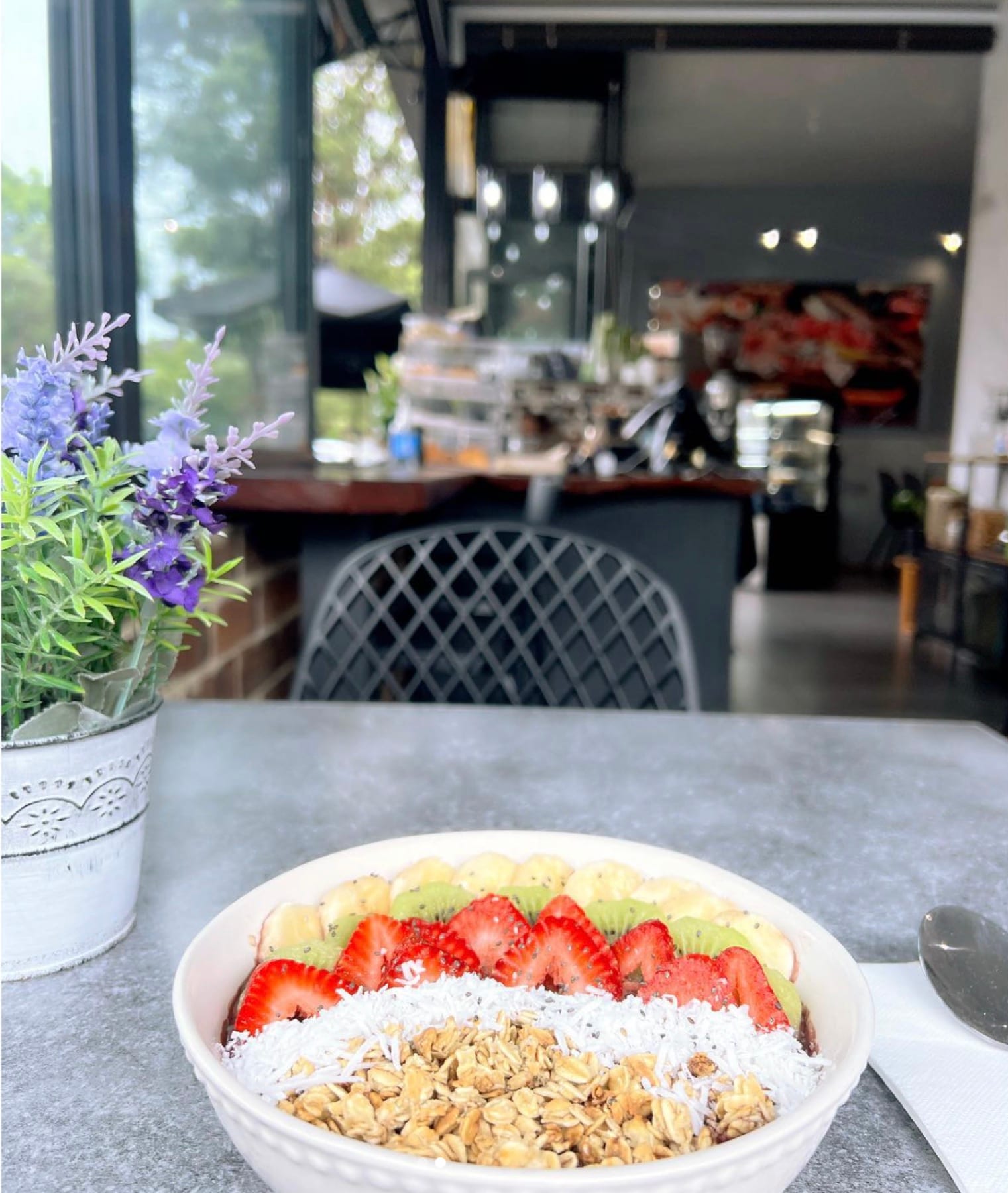 An açaí bowl on a table with the coffee machine and counter out of focus behind