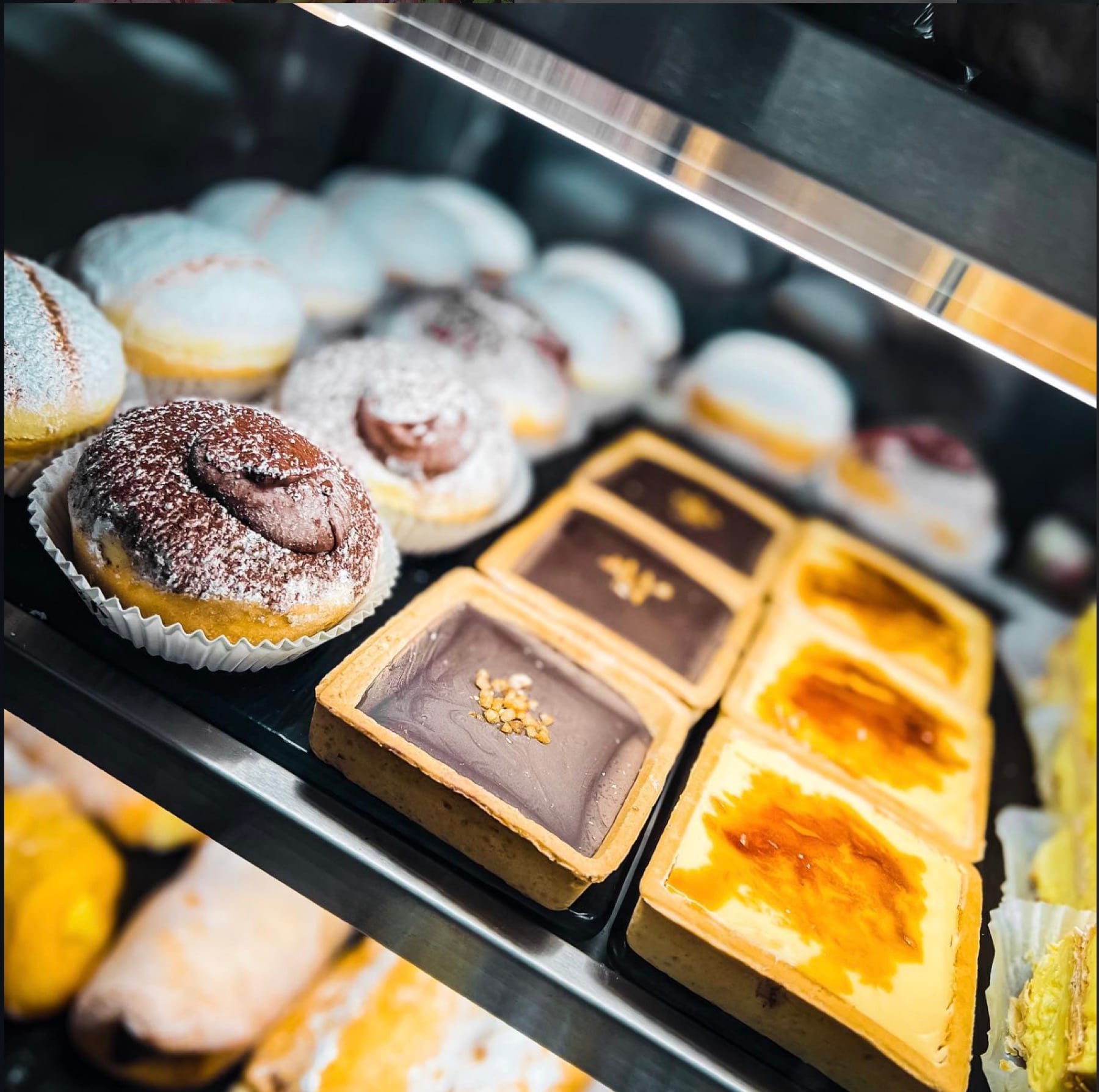 Bakery cabinet with cream buns, chocolate-filled doughnuts and custard tarts