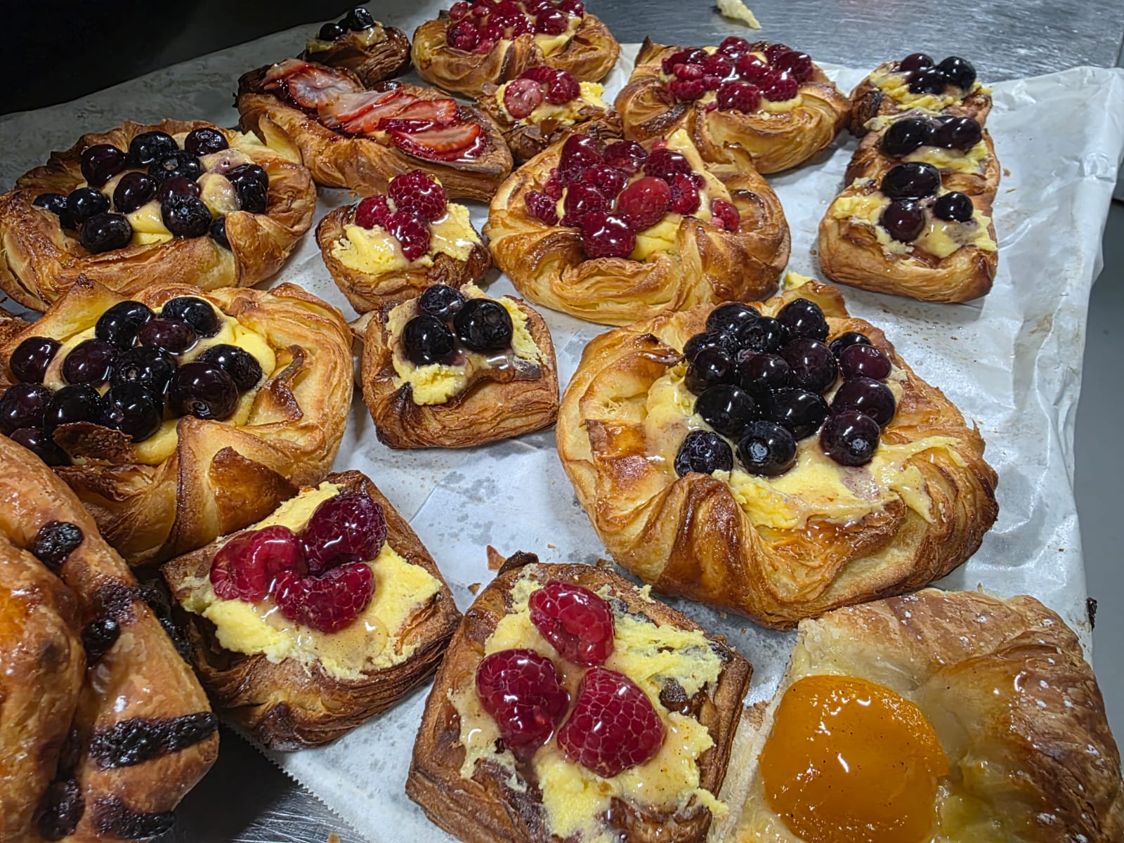 A tray of danishes topped with blueberries, raspberries, strawberries and custard, fresh from the oven
