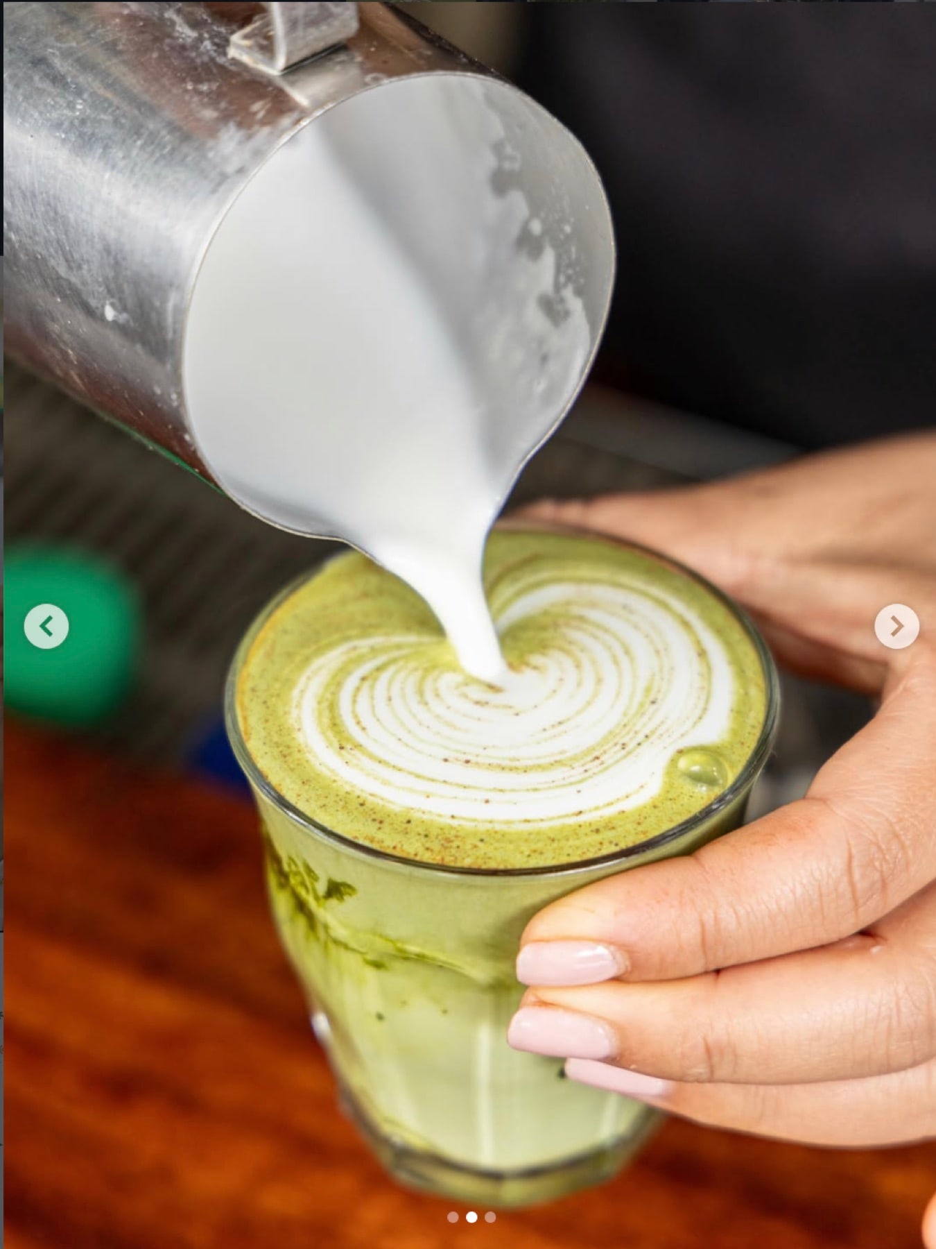 Steamed milk poured into a green matcha latte, forming a spiral