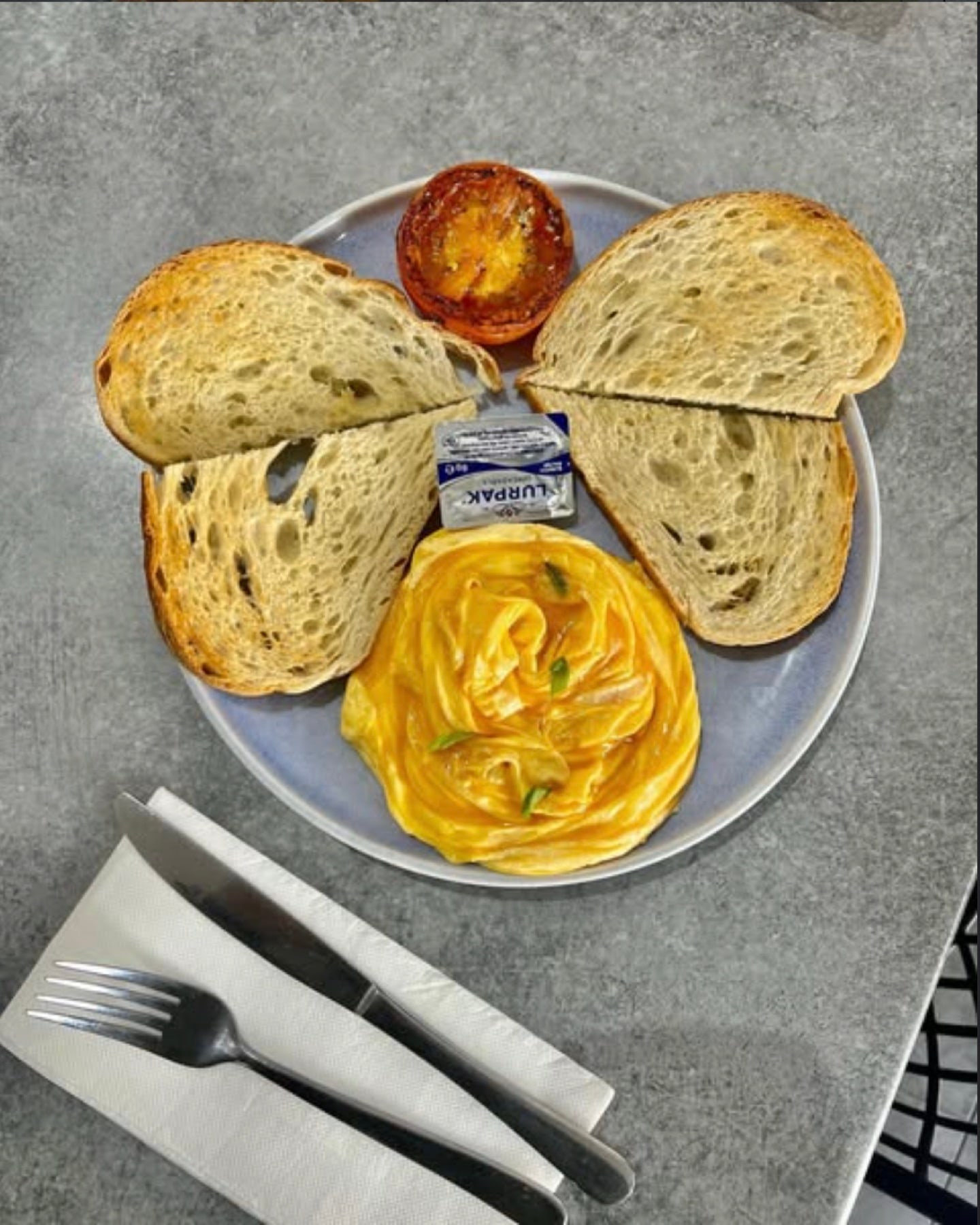 Soft scrambled eggs with grilled tomato and two thick slices of toasted sourdough